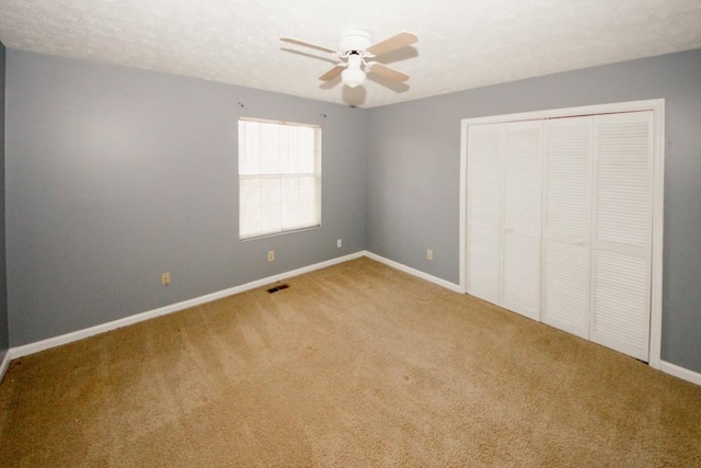 unfurnished bedroom featuring a textured ceiling, a closet, ceiling fan, and carpet flooring