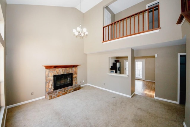 unfurnished living room with an inviting chandelier, a fireplace, high vaulted ceiling, and carpet