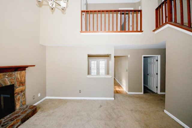 unfurnished living room featuring a fireplace, carpet floors, and a high ceiling