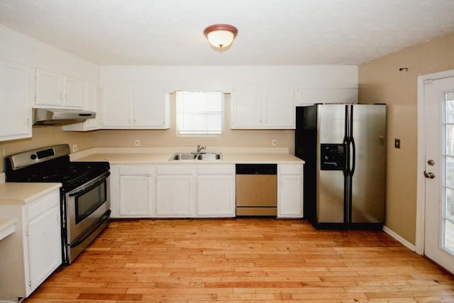 kitchen with stainless steel appliances, sink, white cabinets, and light hardwood / wood-style floors