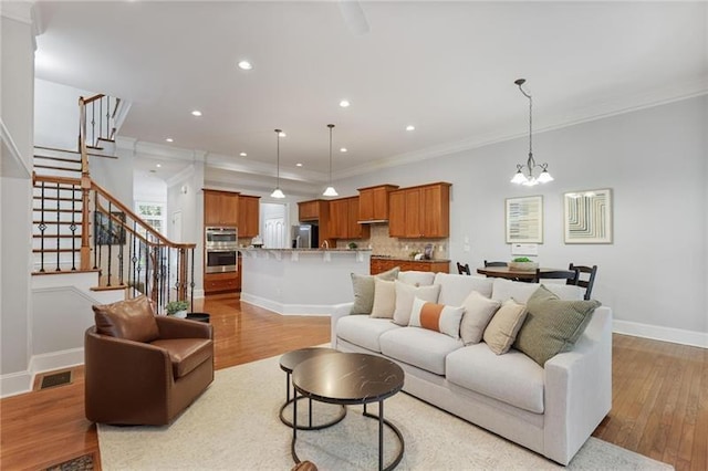 living room with light hardwood / wood-style flooring, an inviting chandelier, and crown molding