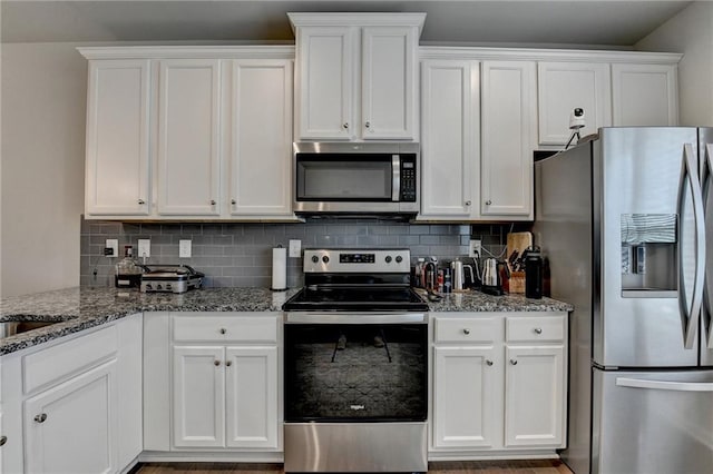 2719 Hedgeway Cir, Kennesaw, GA 30144 - kitchen with appliances with stainless steel finishes, white cabinetry, decorative backsplash, stone countertops, and wood finished floors