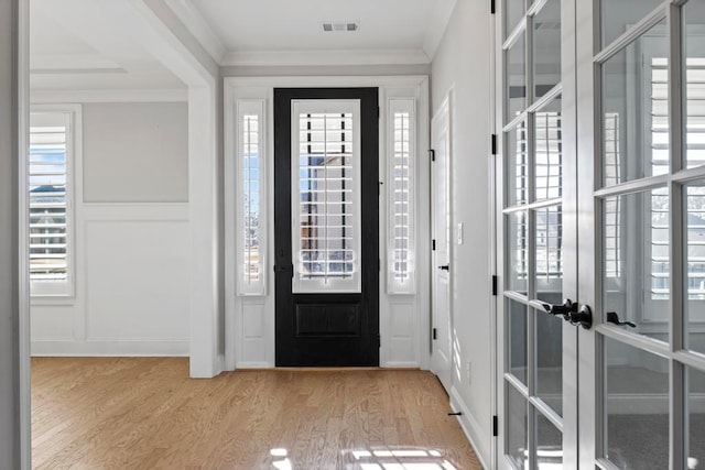 entryway featuring light wood-type flooring, ornamental molding, and french doors