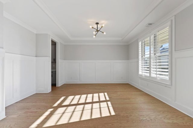 empty room with light hardwood / wood-style flooring, a notable chandelier, and crown molding