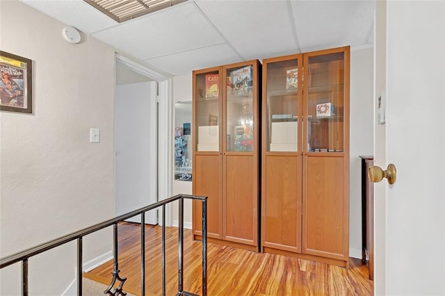 hallway with a drop ceiling and light hardwood / wood-style floors