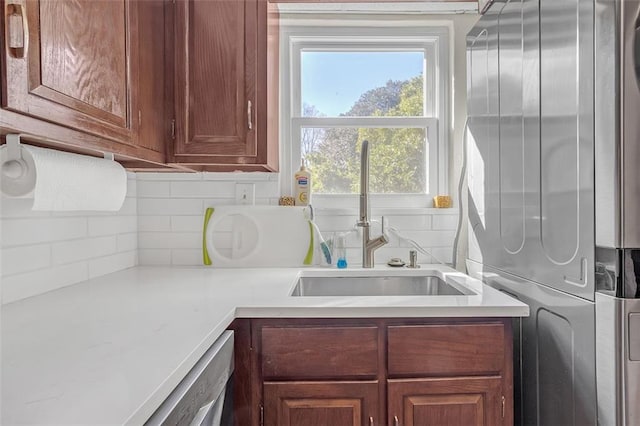 kitchen featuring dishwasher, sink, and stacked washer and clothes dryer