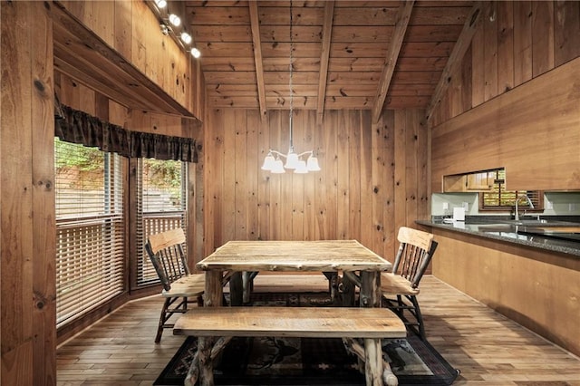 dining space featuring wooden walls, dark wood-style floors, wooden ceiling, lofted ceiling with beams, and a notable chandelier