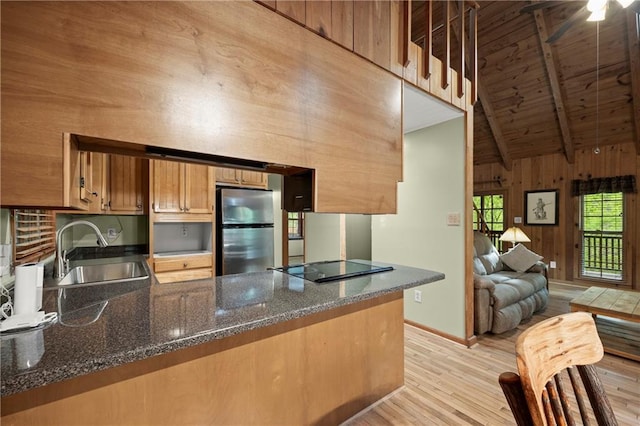 kitchen featuring a sink, freestanding refrigerator, beamed ceiling, a peninsula, and light wood-style floors