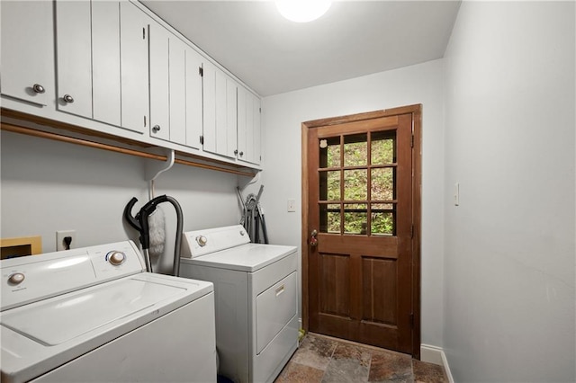 laundry room featuring baseboards, washer and clothes dryer, cabinet space, and stone finish flooring