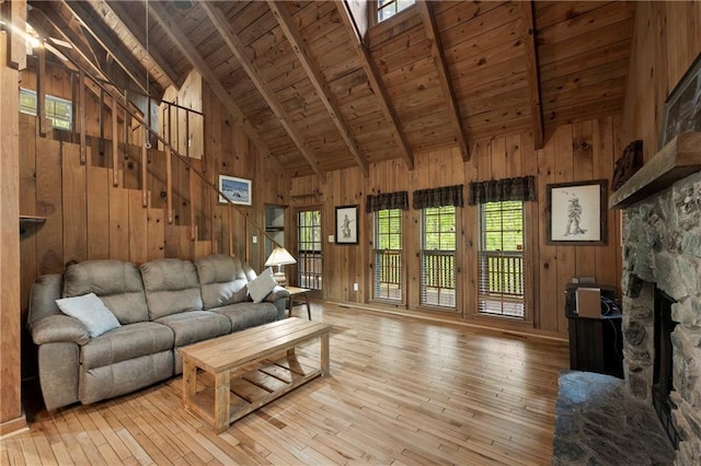 living area featuring wooden walls, wooden ceiling, light wood-style floors, and beamed ceiling