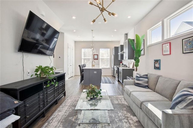 living room with recessed lighting, baseboards, an inviting chandelier, and dark wood-style flooring