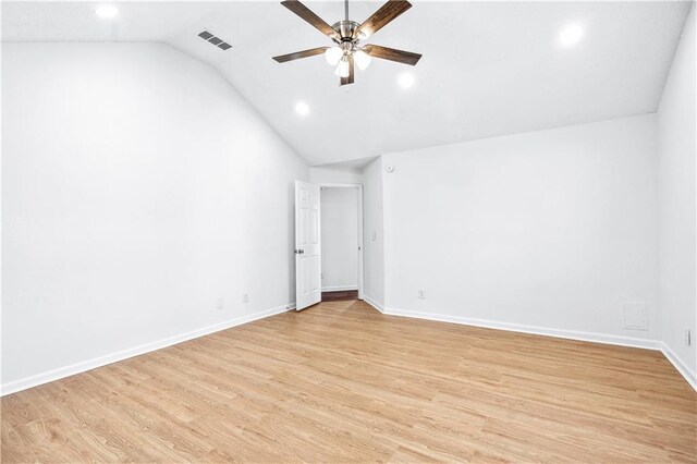 spare room with visible vents, light wood-style floors, a ceiling fan, vaulted ceiling, and baseboards