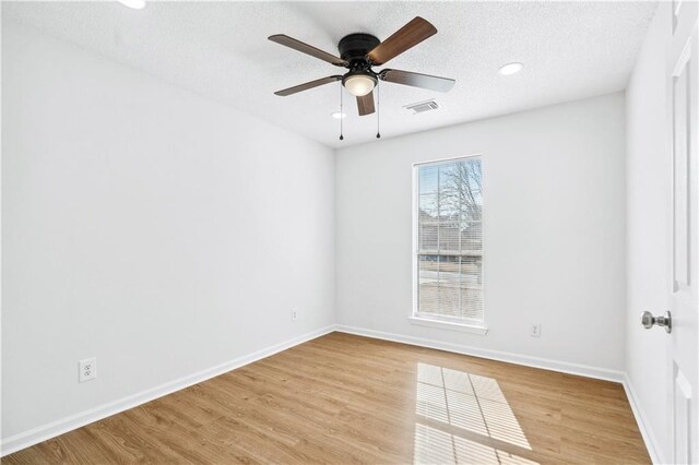 empty room featuring light wood-style flooring, visible vents, baseboards, and a ceiling fan