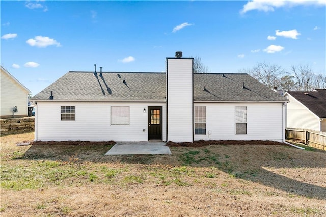 rear view of property featuring a patio, a chimney, fence, and a lawn