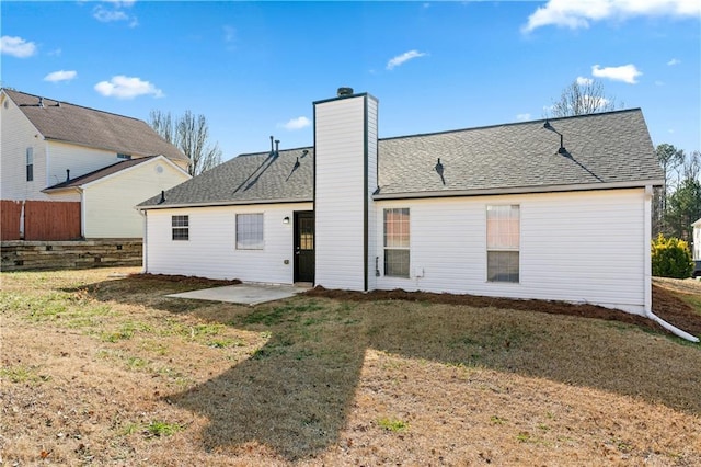 back of house with a yard, a chimney, a shingled roof, a patio area, and fence