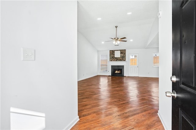 living room featuring a fireplace, a ceiling fan, vaulted ceiling, wood finished floors, and baseboards