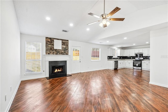 unfurnished living room featuring dark wood finished floors, a fireplace, lofted ceiling, visible vents, and a ceiling fan