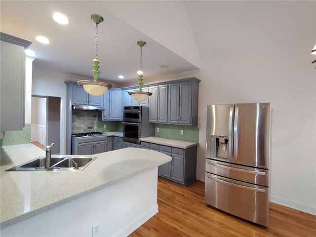 kitchen featuring under cabinet range hood, gray cabinets, a peninsula, stainless steel appliances, and a sink