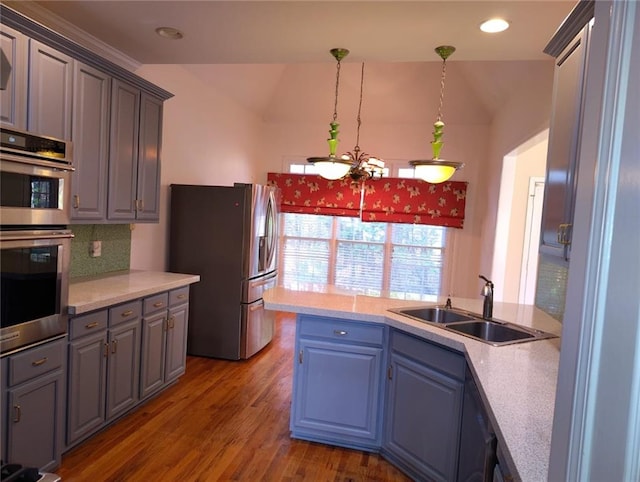 kitchen featuring light countertops, wood finished floors, appliances with stainless steel finishes, and a sink