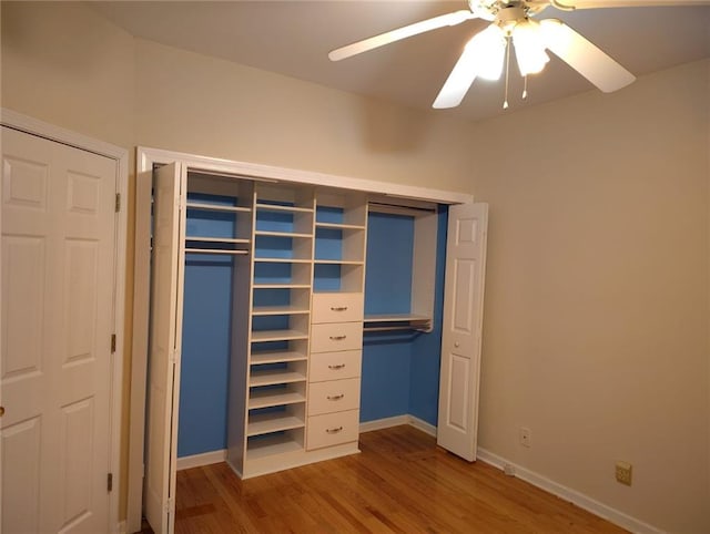 unfurnished bedroom featuring a closet, baseboards, wood finished floors, and a ceiling fan