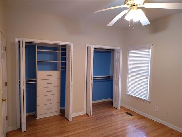 unfurnished bedroom with visible vents, multiple closets, baseboards, and light wood finished floors