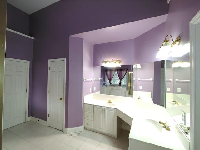 bathroom with tile patterned floors, a sink, baseboards, and double vanity