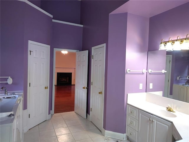 bathroom featuring a high ceiling, a fireplace, vanity, and tile patterned flooring