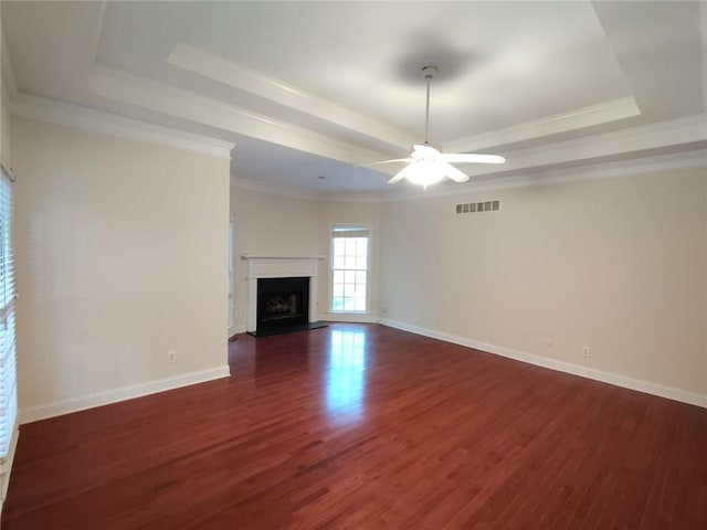 unfurnished living room with visible vents, a fireplace with raised hearth, dark wood-type flooring, and a tray ceiling