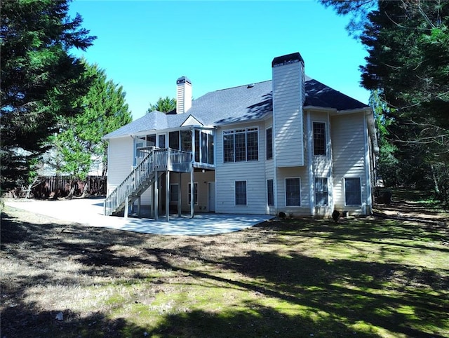 back of house featuring stairs, a patio, a chimney, and a sunroom