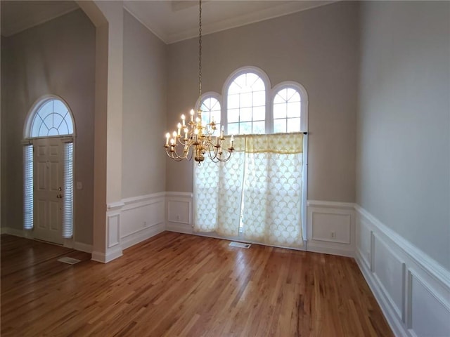 interior space with a notable chandelier, a decorative wall, and wood finished floors