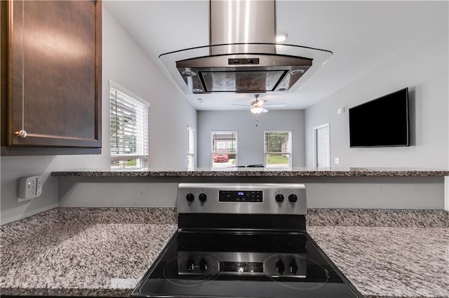 110 Chalfont Cir, Carrollton, GA 30117 - kitchen view of stainless steel electric stove, range hood, dark brown cabinets, ceiling fan, and light stone countertops