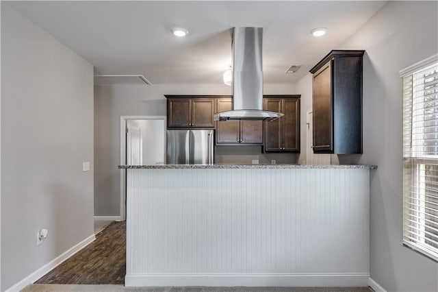 110 Chalfont Cir, Carrollton, GA 30117 - kitchen with freestanding refrigerator, island range hood, dark brown cabinetry, light stone countertops, and baseboards
