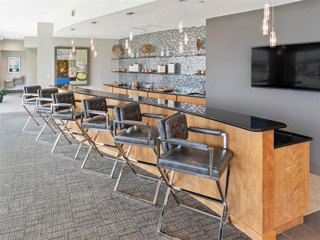 bar featuring dark tile patterned flooring, backsplash, and decorative light fixtures