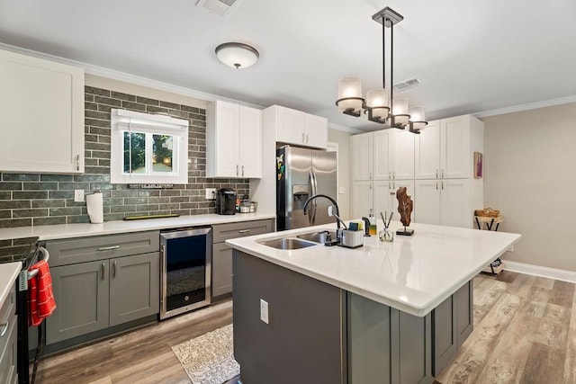 kitchen featuring beverage cooler, stainless steel fridge with ice dispenser, white cabinets, and gray cabinetry