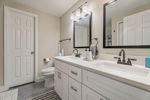 bathroom featuring double vanity, tile patterned flooring, toilet, and a sink