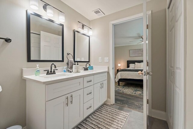 ensuite bathroom with double vanity, visible vents, connected bathroom, ceiling fan, and a sink