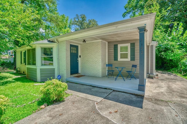 view of front of house with brick siding, a patio, and a front lawn