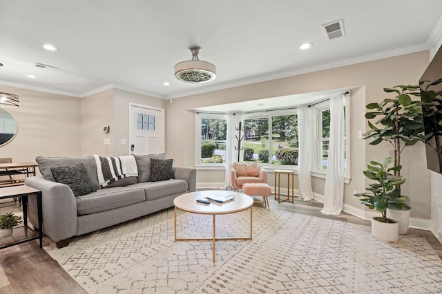 living room featuring baseboards, ornamental molding, visible vents, and light wood-style floors