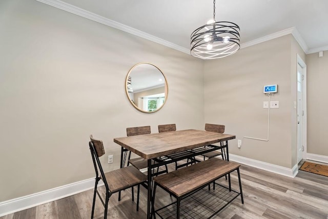 dining space with an inviting chandelier, baseboards, crown molding, and wood finished floors