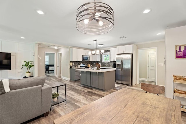 kitchen featuring gray cabinetry, light countertops, appliances with stainless steel finishes, a center island, and pendant lighting