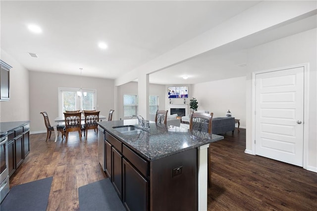 kitchen with pendant lighting, dishwasher, dark stone counters, sink, and dark hardwood / wood-style flooring