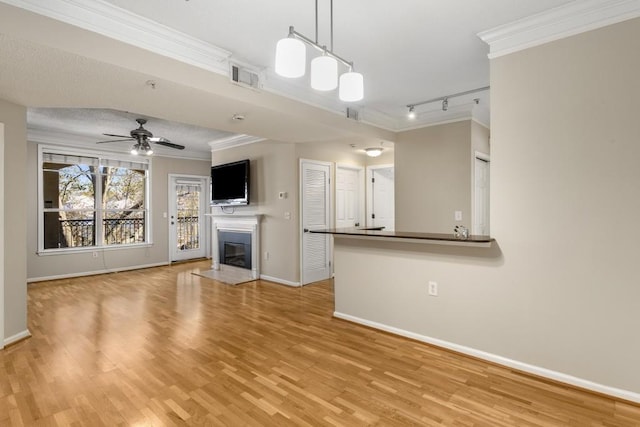 unfurnished living room with ornamental molding, rail lighting, ceiling fan, and light wood-type flooring