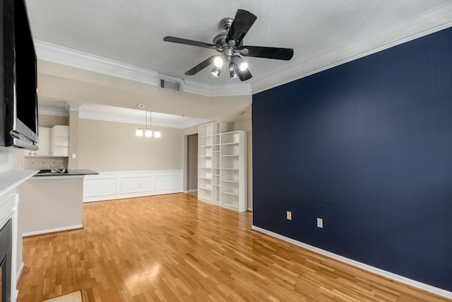 unfurnished living room featuring ornamental molding, ceiling fan with notable chandelier, a textured ceiling, and light wood-type flooring