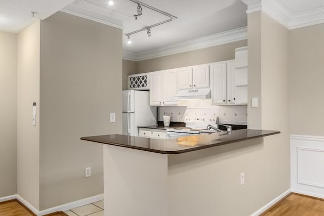 kitchen featuring rail lighting, white cabinets, ornamental molding, kitchen peninsula, and white appliances