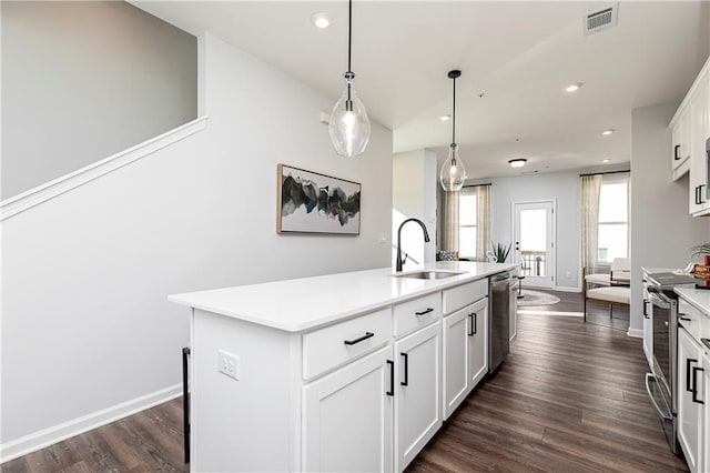 kitchen with visible vents, a sink, a center island with sink, appliances with stainless steel finishes, and dark wood-style flooring
