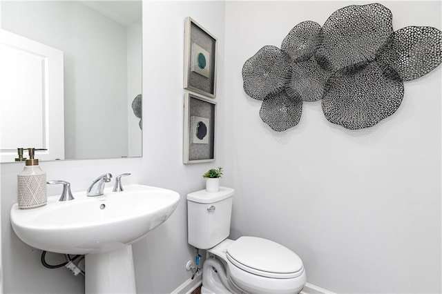 half bath featuring toilet and baseboards
