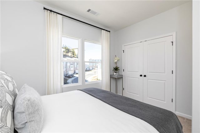 bedroom featuring baseboards, visible vents, carpet floors, and a closet