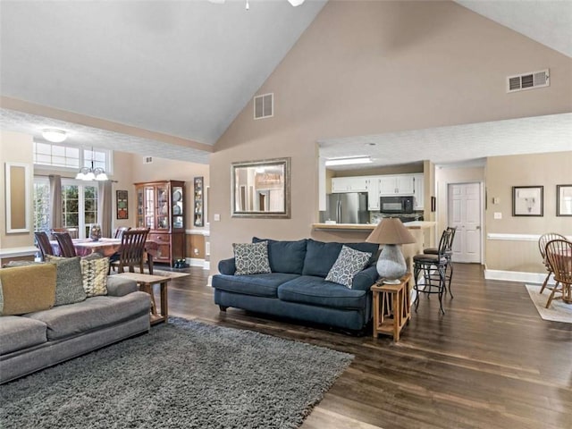 living room featuring an inviting chandelier, dark wood-type flooring, and high vaulted ceiling