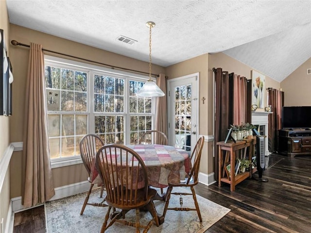 dining area featuring lofted ceiling, dark wood-type flooring, and a textured ceiling