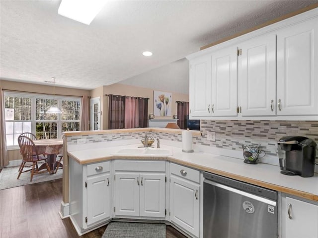 kitchen featuring decorative light fixtures, dishwasher, sink, white cabinets, and kitchen peninsula